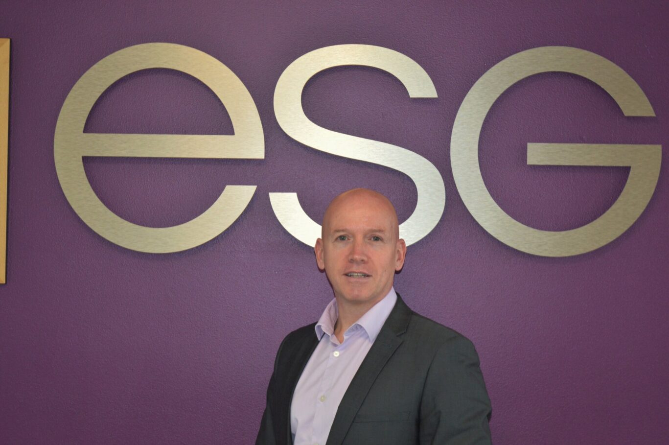 David Hoey Managing Director stands against wall displaying ESG letters.